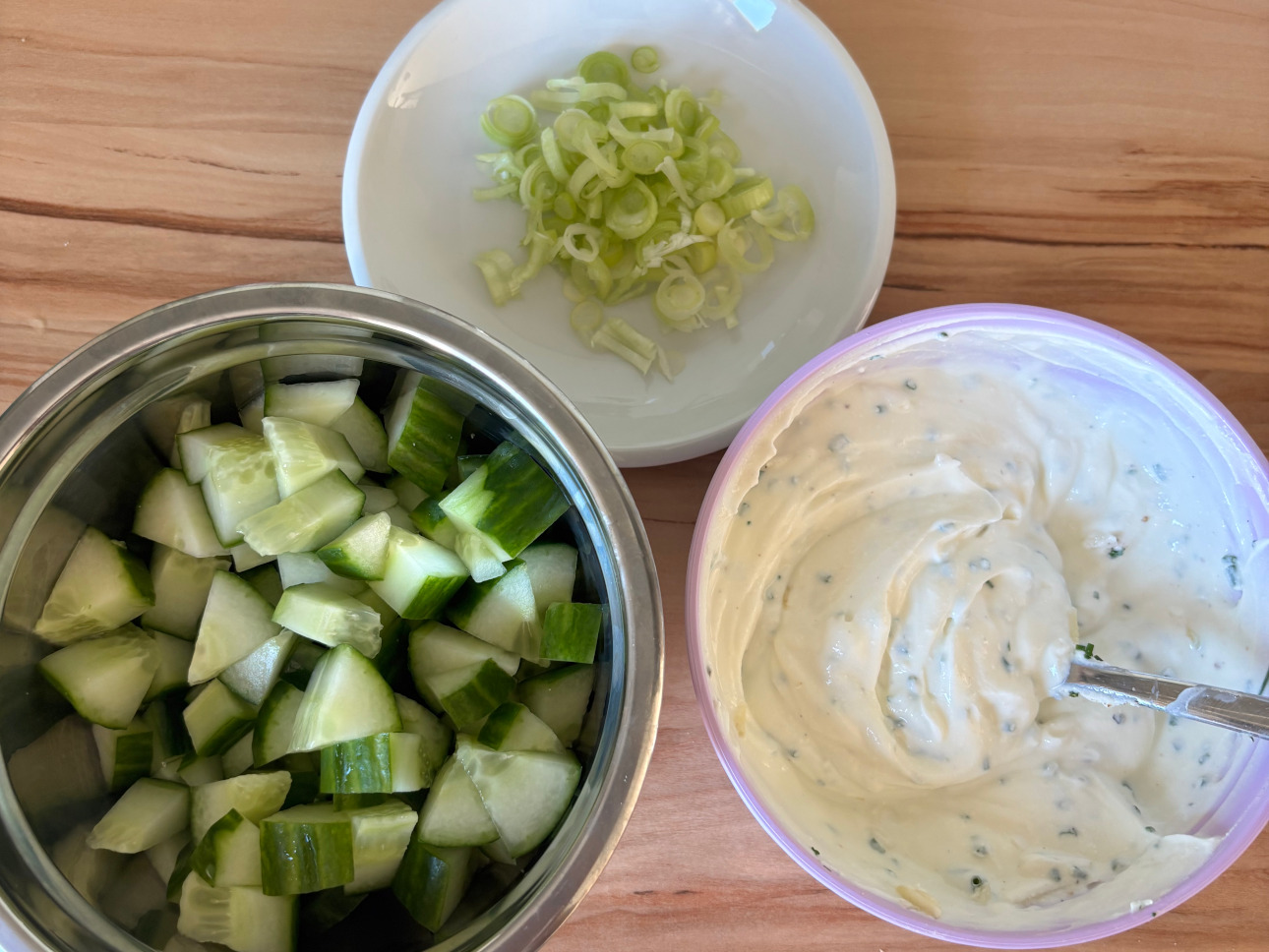 Gurken, Frühlingszwiebeln schneiden, Salat waschen und Joghurt-Sauce zubereiten